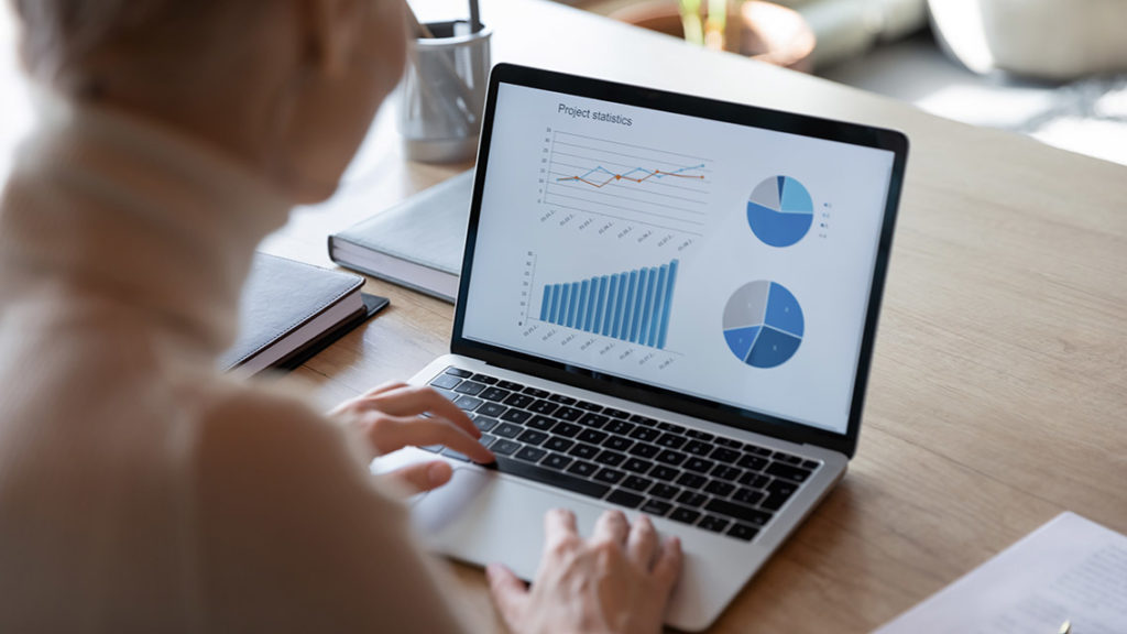 Sales charts on laptop screen view over businesswoman shoulder